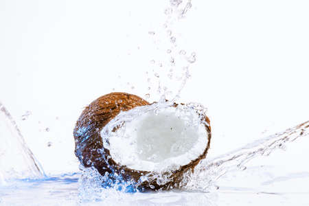 cracked coconut with big splash, isolated on whiteの写真素材