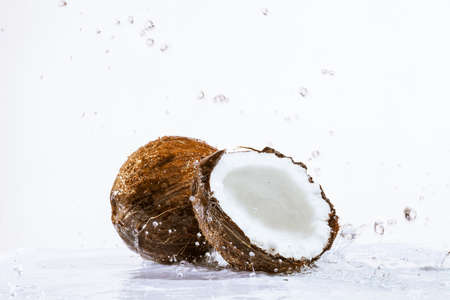 cracked coconut with big splash, isolated on whiteの写真素材