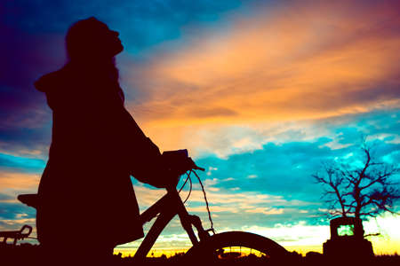 Girl with a bicycle watching the sunsetの写真素材