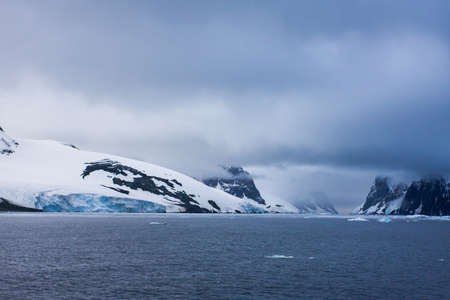 Beautiful snow-capped mountains against the white fog in Antarcticaの写真素材