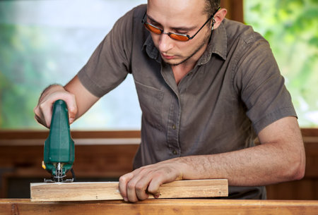Young man working with wood. Natural background behind