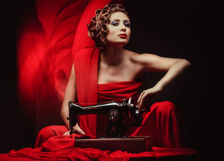 beautiful young pinup woman with sewing machine in red material