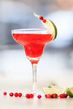 cosmopolitan cocktail garnished with a lime and berries