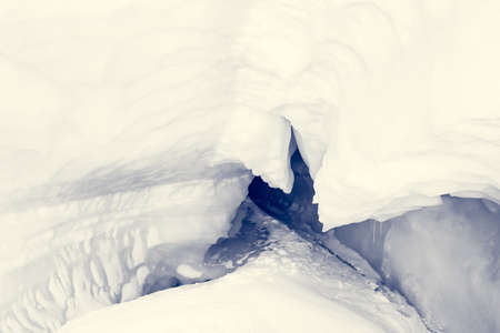 blue ice cave covered with snow and flooded with lightの写真素材