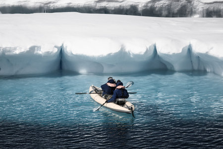 Two men in a canoe among icebergs in Antarctica