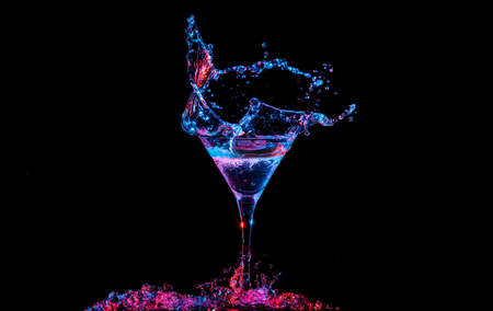 Bright cocktail with lemon in glass and splashing water on dark backgroundの写真素材