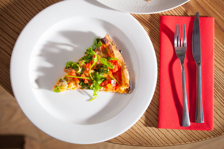 Delicious appetizer on white plate with fork and knife on red napkin close up
