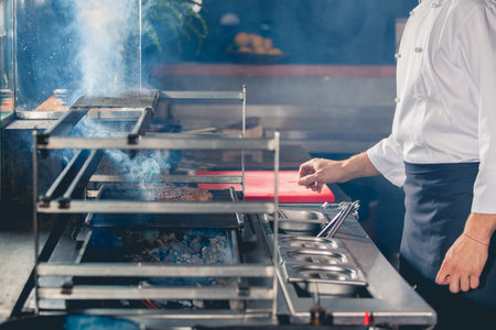 young male cook preparing meal on the grillの写真素材