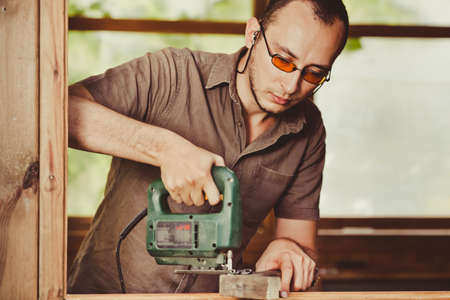 Young man working with wood. Natural background behindの写真素材