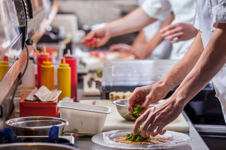male cooks preparing meals in restaurant kitchenの写真素材