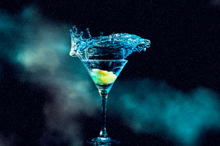 cocktail in glass with splashes and lemon on dark smoky background. Party club entertainment.の写真素材