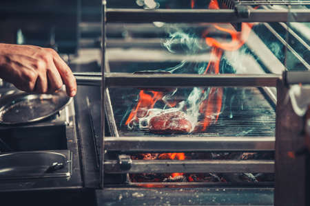 young male cooks preparing meal on the grillの写真素材