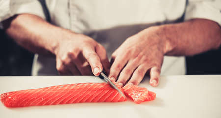 Cook hands cutting fresh salmon fillet close-upの写真素材