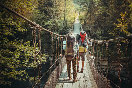 Travelers crossing through hanging bridge in good sunny day over the lakeの写真素材