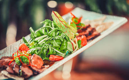 Delicious salad with herbs and meat on white plate close upの写真素材