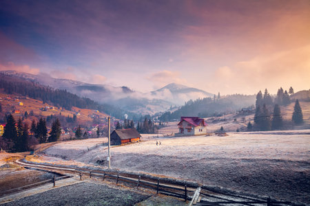 Colorful winter landscape in the mountain village. Foggy morning with dramatic pink sky. Carpathians, Ukraine, Europe. Exploring beauty world. Beautiful nature landscape. Travel background.の写真素材