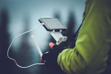 Man in green jacket operating a drone using a remote controller. Winter holidays in mountains. Close up picture. Bukovel, Carpathians, Ukraine, Europe. Exploring beauty worldの写真素材