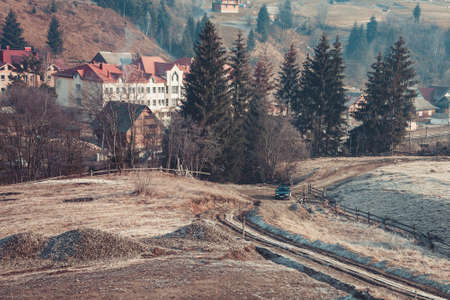 Beautiful autumn in mountain village. Car driving on a country road. Pine trees on the sides. Carpathians, Ukraine, Europe. Exploring beauty worldの写真素材