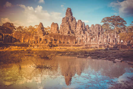 Angkor Wat Temple in Cambodia reflected in lake. Largest religious monument complex in the world. Ancient Khmer architecture. Orange ancient ruins against blue sky. Retro vintage toningの写真素材