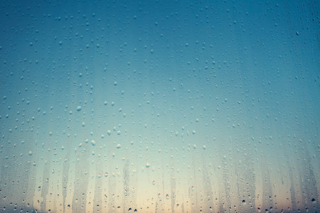 Transparent drops of water on the glass surface. Color transition from yellow to blue shades. Matte...