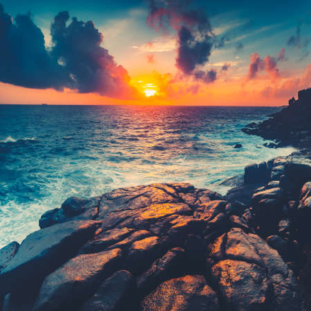 Breathtaking bright sunset over the Indian Ocean. Unawatuna, Sri Lanka. Amazing colorful sky, royal blue ocean and mighty shore boulders. Perfect image for the illustrations and collages.の写真素材