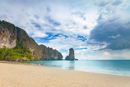 Stunning scene the limestone cliffs covered with the vegetation and the ocean shore on the cloudy sky background. Beauty of wild virgin Thai nature. Ideal place for the calm rest.の写真素材