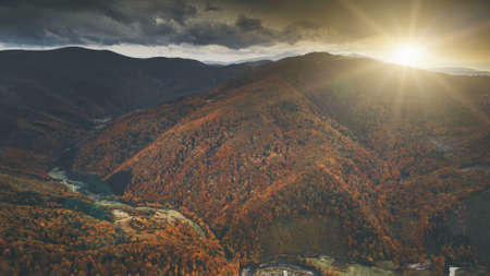Aerial View over dramatic autumn canyon mountain landscape. Green meadows, orange hills, pine tree forests against sunset sky. Carpathians, Ukraine, Europe. Vintage retro dark toning filter.の写真素材