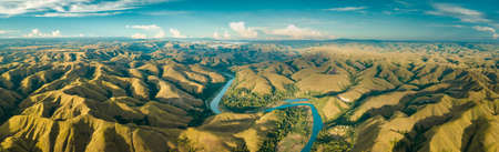 Panoramic view river, hills. Aerial drone shot. Indonesia. Spectacular landscape of Sumba island. Blue sky with white clouds . Beauty of wild untouched nature.の写真素材