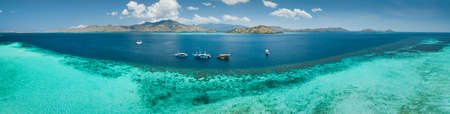 Aerial drone panoramic shot ocean, Komodo background. Transparent turquoise water of the Pacific ocean with the boats taken for tourist reasons. Komodo National Park, Indonesia.の写真素材