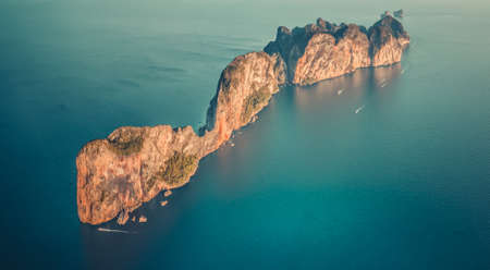 Aerial drone top view on lonely island in Indian ocean. Koh Phi Phi Leh tropical rock island with tourist boats around, Thailand. Travel Background. Nature landscape. Vintage toning filterの写真素材
