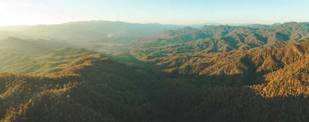 Panoramic autumn overview. North Thailand mountain valley. Aerial drone shot. Breathtaking scenery of orange colored sunlit hills. Beauty of wild untouched virgin nature. Exotic travel. Wilderness.の写真素材