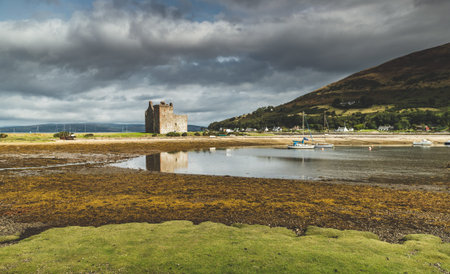 Lochranza castle next to the Arran island bay. Scotland. Amazing countryside landscape. Ancient building on the Scottish shoreline. Autumn scene. Grey cloudy sky before the rain.の写真素材