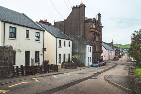 Ancient buildings on the cozy street. Northern Ireland. Small town scenery. Historic stone houses on the attractive narrow street. Vintage retro style. Victorian epoque. The landscape in brown tints.の写真素材