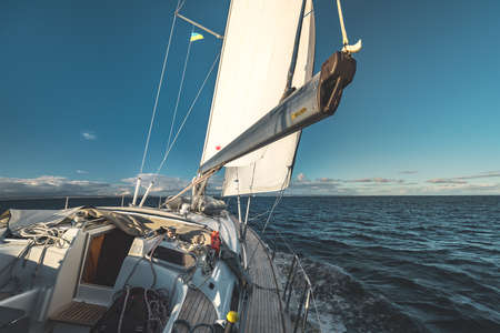 Close-up deck view. Yacht sailing next to the Northern Ireland shore. Boat equipment. The stunning overview from the bow yacht. Sea water surface. Amazing marine landscape.の写真素材