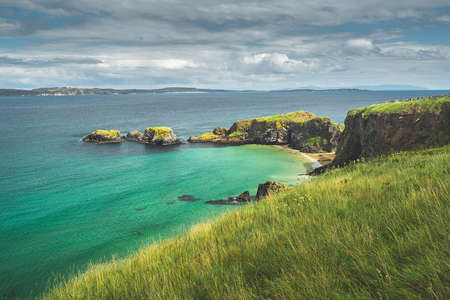 Irish bay with turquoise water and grass covered land. Northern Ireland. Breathtaking marine landscape. Grass covered land of the stunning shoreline. Beauty of wild untouched nature.の写真素材