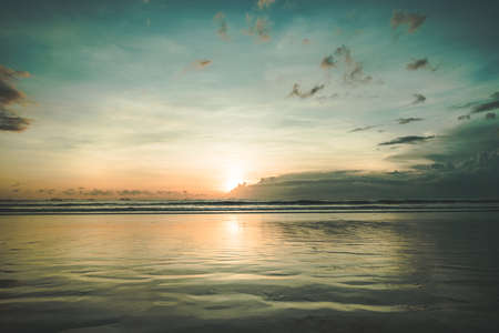 The sunset over the calm water surface. Picturesque twilight Asian landscape. The fall sun in the colorful sky over the ocean body. The peacefulness. Ideal place for the rest and relax.の写真素材
