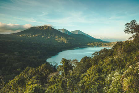 The lake Batur surrounded by the greens and volcano. Bali island, Indonesia. Picturesque overview of the water surface among the dense woods. Popular tourist attraction. Amazing Balinese landscape.の写真素材