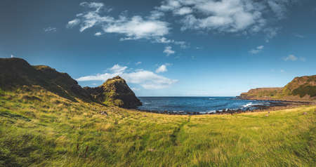 Green grass covered meadow next to the ocean. Northern Ireland panoramic view. Overwhelming horizon background. Perfect image for the creating of the different kinds collages and illustrations.の写真素材