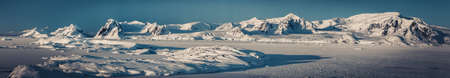 Panorama view of Antarctica nature, sunlit snow covered Penola bay. Stunning aerial shot. The ice surface of the South Pole. Picturesque snow covered mountains next to the frozen Antarctic shorelineの写真素材