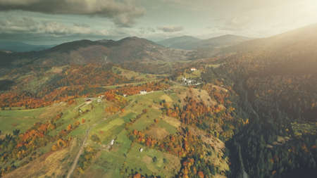 Autumn Multi Colored Mountain Landscape Aerial View. High Hill Tree Forest Scenery, Cloudy Sky. Green Slope Surface Countryside Village. Clean Ecology, Travel Concept. Drone Flightの写真素材