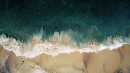 Aerial Top Drone View on Ocean Waves and White Sand Beach. Crystal Water Landscape in Tropical Bali Island, Indonesia. People Walk, Swim and Relax. Cinematic Filter Toningの写真素材