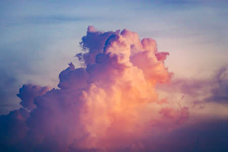 Close-up colorful clouds going up in sunset sky. Natural phenomena. Atmospheric environment. Splash of rose, scarlet and blue tints. Great background for different kinds of collages and illustrations.の写真素材