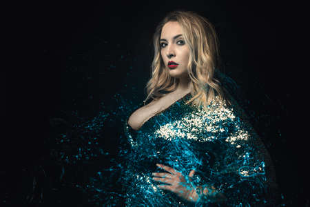 Blond Woman with Blue Bright Sparkles Element Copy Space. Standing Fashionable Girl Plus Size Model Studio Photo Black Background. Glamor Positive Caucasian Female Looking Away Front Viewの写真素材