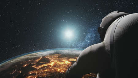 Cosmonaut looking at realistic planet Earth orbit. Sunrise over illuminated mainlands. Astronaut back view. 3d render animation. Science, technology concept.の写真素材