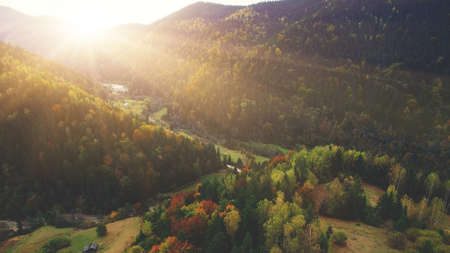 Aerial Drone View: Flight over autumn mountain village with forests, fields and river in sunrise soft light. Carpathian Mountains, Ukraine, Europe. Majestic landscape. Beauty world.の写真素材