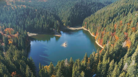 picturesque calm deep blue lake reflecting green tree silhouettes against forestry hills in autumn upper view. Carpathian mountains, Ukraine beauty nature. Travel, summer holidays.の写真素材