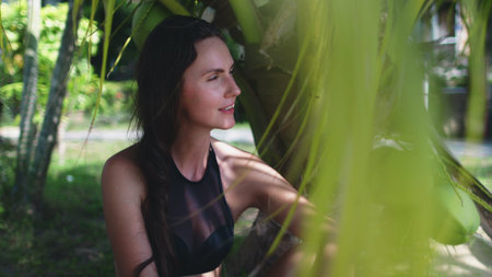 Peaceful Woman Spending Time at Exotic Seaside. Carefree Caucasian Girl in Bikini Sitting under Coco Palm at Tropical Coastline. Koh Phangan Island, Thailand.の写真素材