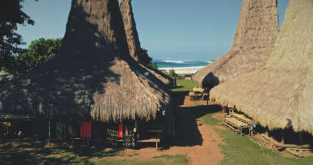 Closeup traditional houses with ornately roofs at green countryside village. Exterior of primitive settlement with long-held tradition at Sumba Island, Indonesia, Asia. Cinematic soft light shotの写真素材