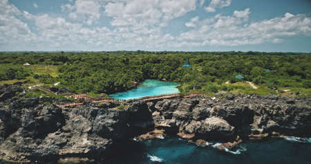 Cliff ocean coast with limpid lake on green top aerial view. Picturesque Indonesia landscape at tropic greenery nature of Weekuri lagoon, Sumba Island. Cinematic soft light summer sceneryの写真素材