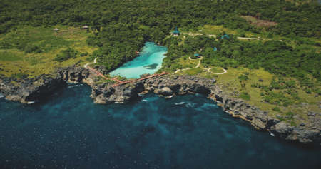 Green rock shore at ocean bay with tropical salt water lake aerial view. Nobody tropical nature landscape with turquoise lagoon at sea coast of Weekuri, Sumba island, Indonesiaの写真素材